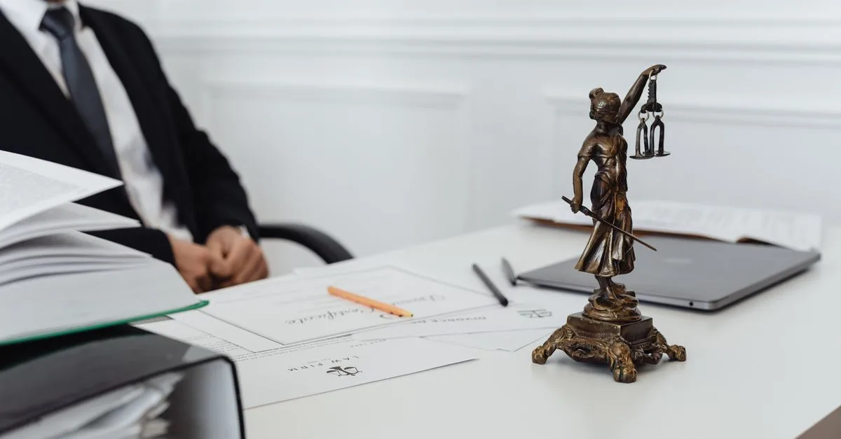 A legal professional's workspace featuring Lady Justice statue, documents, and a laptop.