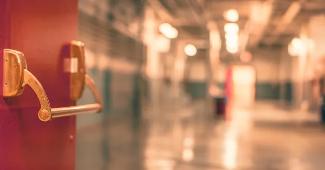 Abstract image of a blurred industrial corridor with focus on a red door handle.