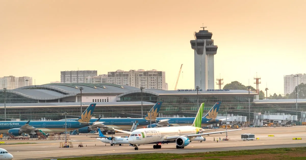 Airplanes parked on a runway under a dramatic golden sunset sky at a modern airport terminal.