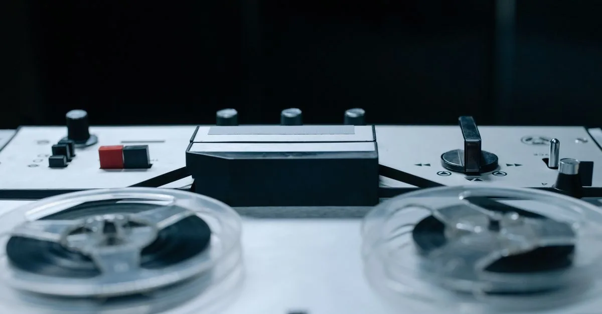 Close-up image of a vintage reel-to-reel audio recorder with control buttons and tape reels.