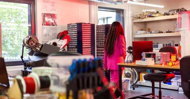 A woman in a pink suit exploring a colorful and modern laboratory environment.