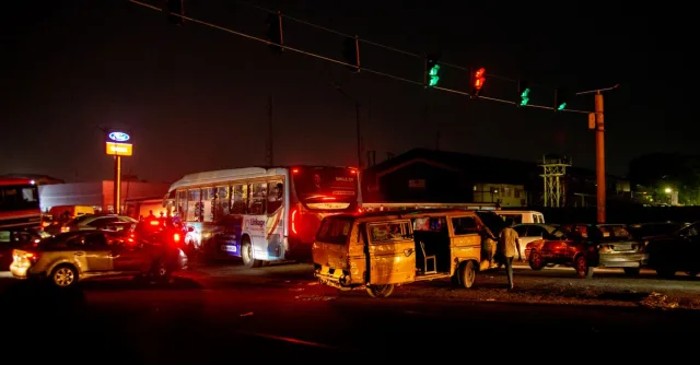 A crowded urban nighttime scene featuring a traffic accident at a busy intersection.