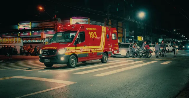 Red emergency transport near  car crash on illuminated night street in modern city