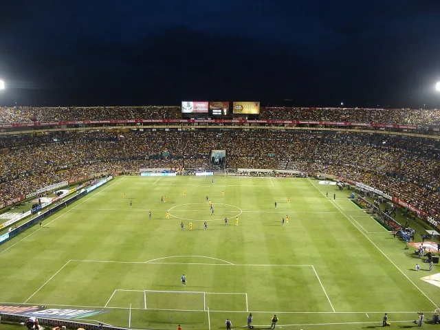A professional football stadium illuminated by bright floodlights at night.