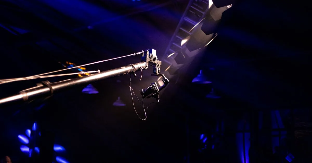Camera crane setup at a concert venue with dramatic lighting and vivid colors.