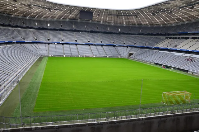 An empty professional football pitch under stadium lights.