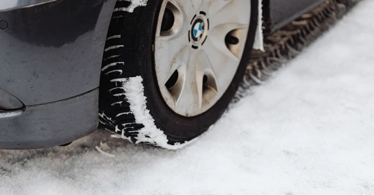 Close-up of a car's tire on a snowy road, highlighting the winter season conditions.