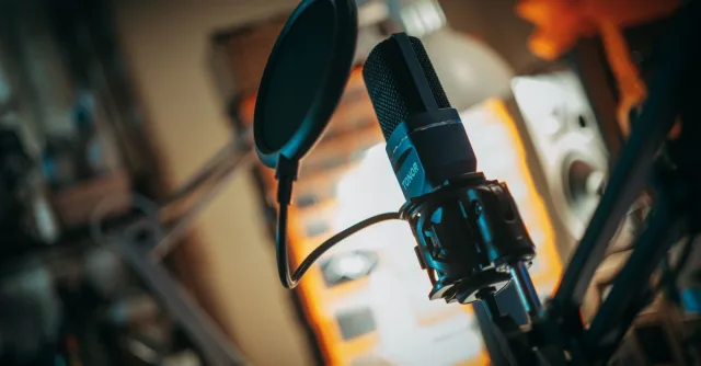 Close-up of a microphone with pop filter in a recording studio, perfect for music production visuals.
