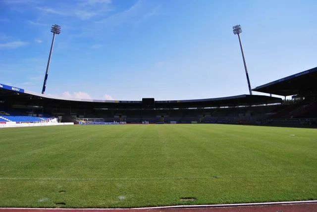 A professional football stadium illuminated by bright floodlights at night.