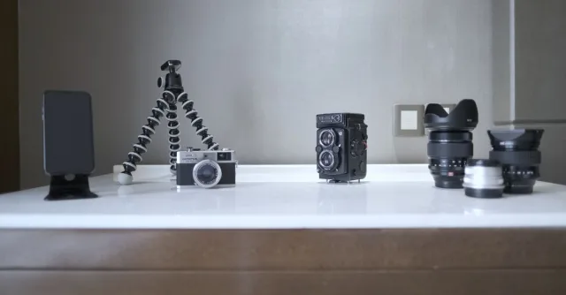 A collection of vintage and modern photography equipment, including cameras and lenses, creatively arranged on a table.