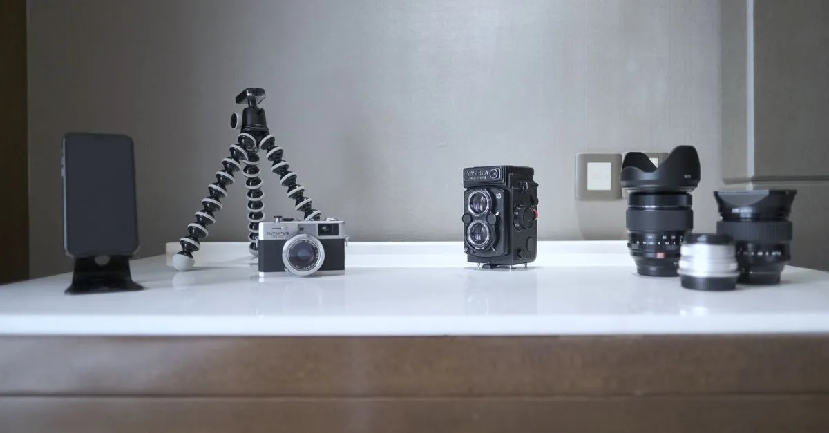 A collection of vintage and modern photography equipment, including cameras and lenses, creatively arranged on a table.