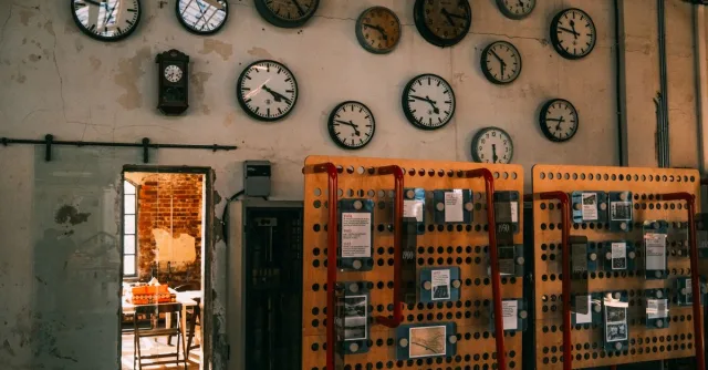An array of vintage wall clocks in a dimly lit industrial setting, highlighting time and nostalgia.