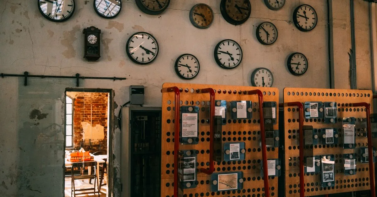An array of vintage wall clocks in a dimly lit industrial setting, highlighting time and nostalgia.