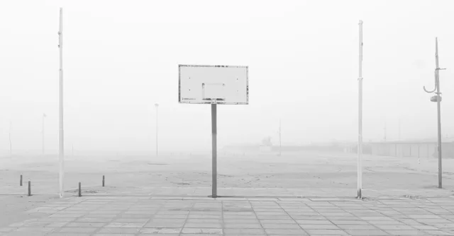 Foggy outdoor basketball court in black and white, showcasing a minimalistic and serene atmosphere.