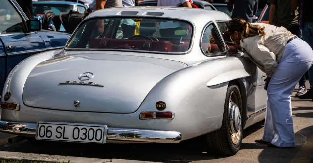 Vintage Mercedes-Benz 300 SL showcased at Ankara car event. Enthusiast peering inside the iconic vehicle.