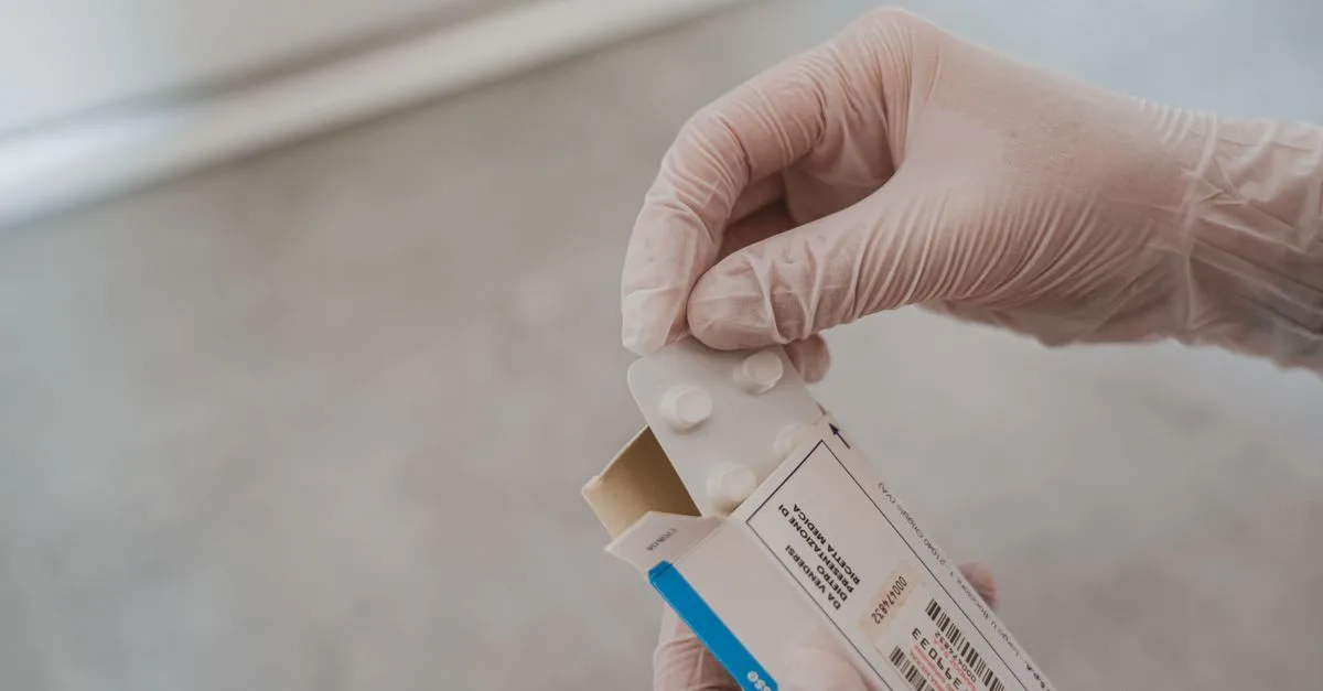 Close-up of hands in gloves handling medication blister pack, ensuring safety and hygiene in healthcare.