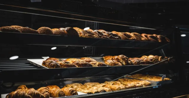A variety of freshly baked pastries and breads in a glass display case at a bakery.