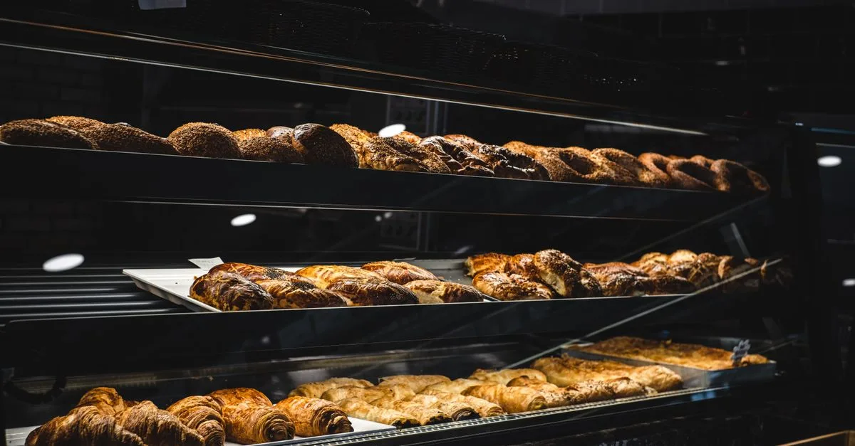 A variety of freshly baked pastries and breads in a glass display case at a bakery.