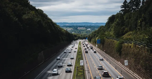 A bustling highway cuts through lush forests under a cloudy sky in Herford, Germany.