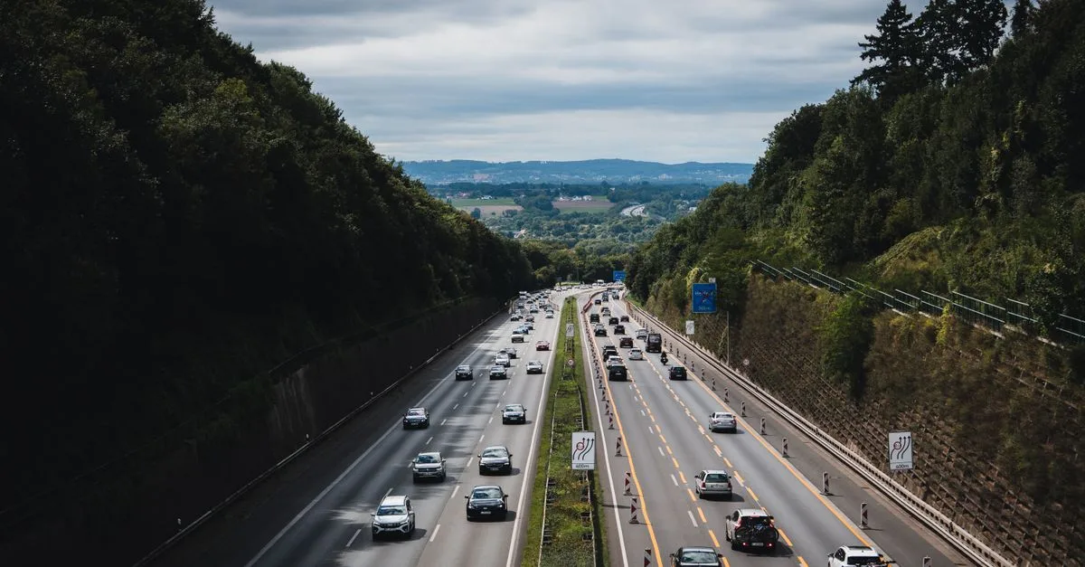 A bustling highway cuts through lush forests under a cloudy sky in Herford, Germany.