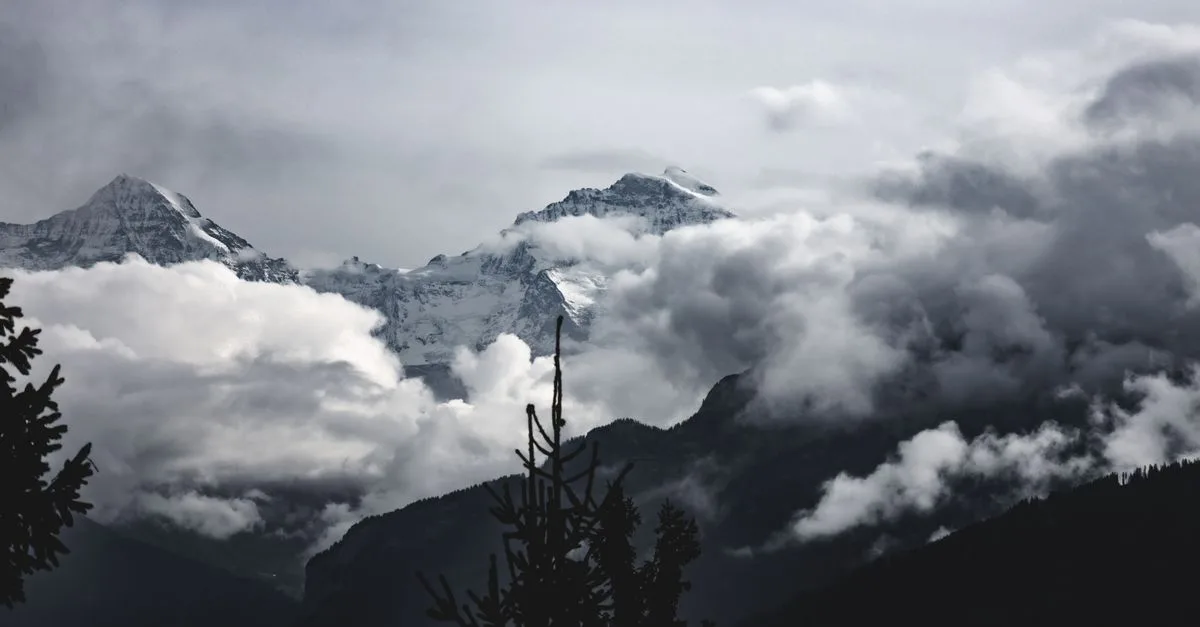A stunning view of snowcapped peaks amidst dramatic clouds in Interlaken, Switzerland.