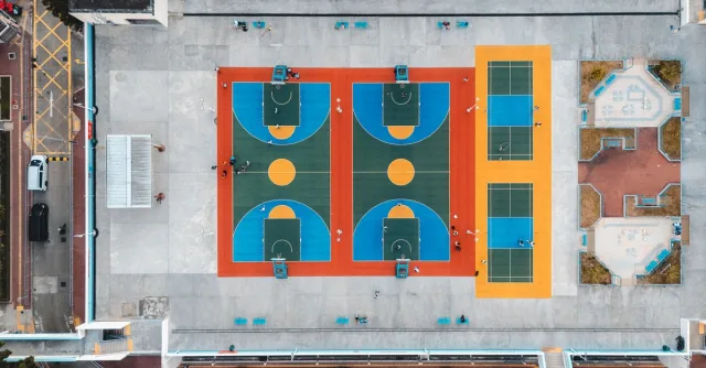 Aerial shot of vibrant basketball and tennis courts in Kowloon, Hong Kong, showcasing urban recreation.