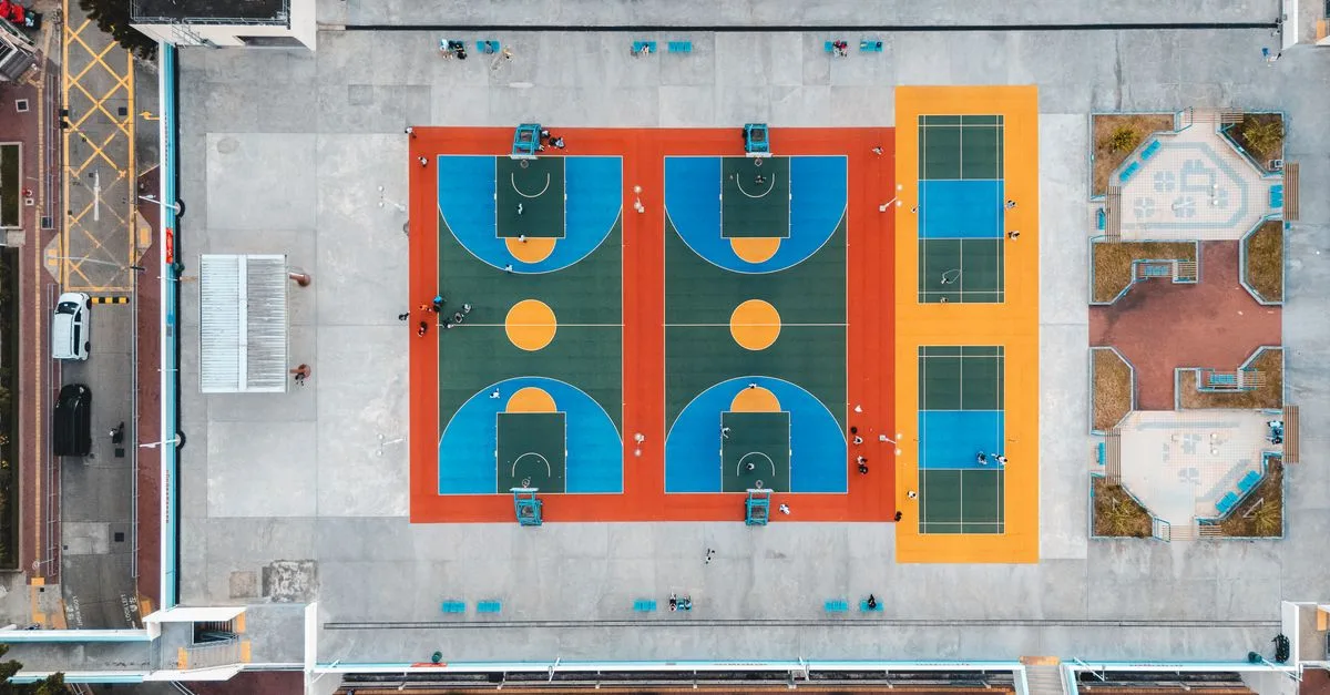 Aerial shot of vibrant basketball and tennis courts in Kowloon, Hong Kong, showcasing urban recreation.