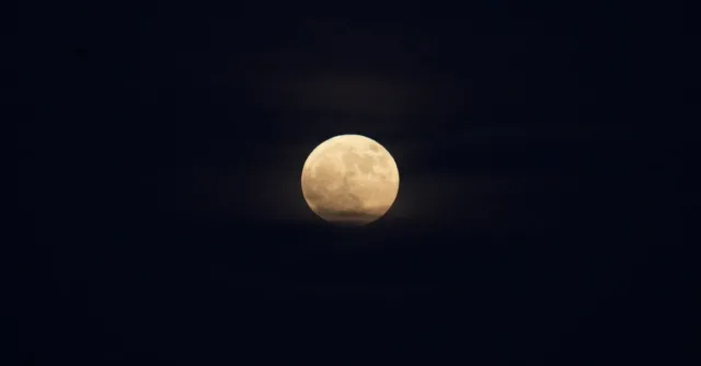 A luminous full moon surrounded by a dark, clear night sky, offering a serene celestial view.