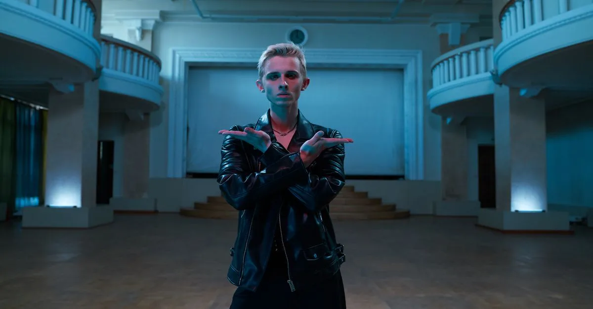 Contemporary dancer striking a pose in an elegant, vintage ballroom setting wearing a leather jacket.