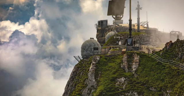 Dramatic mountain observatory with radar and clouds, offering a majestic aerial view.