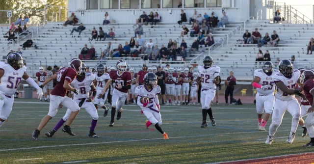 Exciting football match with young athletes in action on the field at an outdoor stadium.