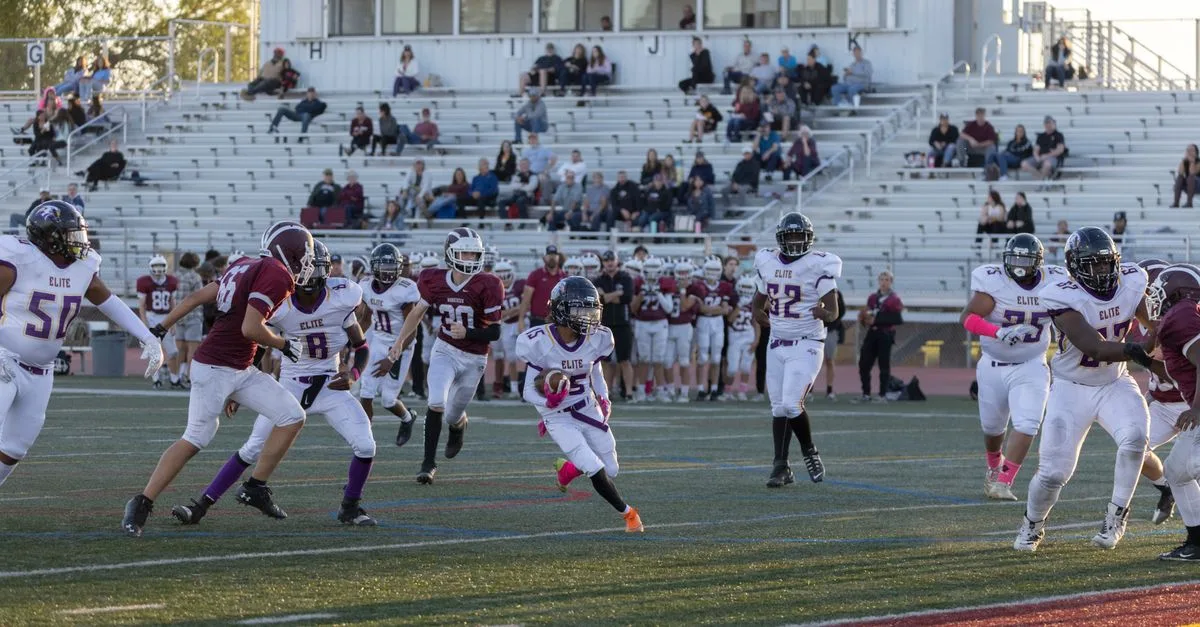 Exciting football match with young athletes in action on the field at an outdoor stadium.