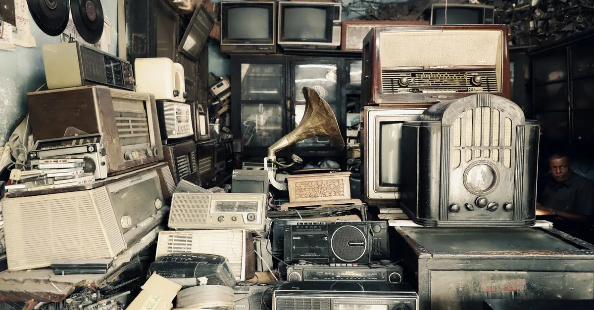 An array of vintage electronics, radios, and a gramophone in an antique shop with a nostalgic atmosphere.