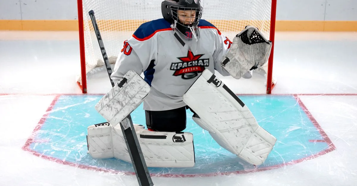 Young hockey goalie in full gear defends the ice hockey goal with focus and determination.