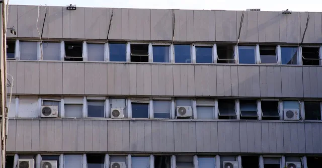 Urban building facade with multiple windows and air conditioners in İzmir, Türkiye.