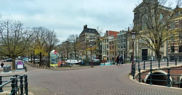 An empty cobblestone canal bridge in Amsterdam with classic Dutch architecture in autumn.