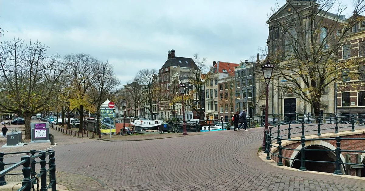 An empty cobblestone canal bridge in Amsterdam with classic Dutch architecture in autumn.
