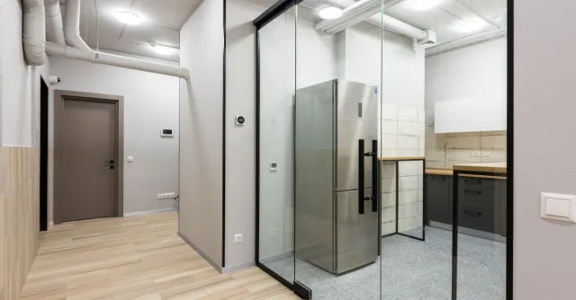 Interior of spacious hallway and kitchen with counters and appliances in contemporary workplace