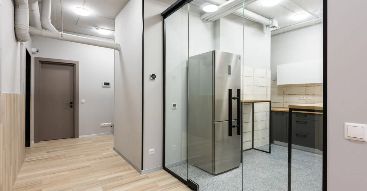 Interior of spacious hallway and kitchen with counters and appliances in contemporary workplace