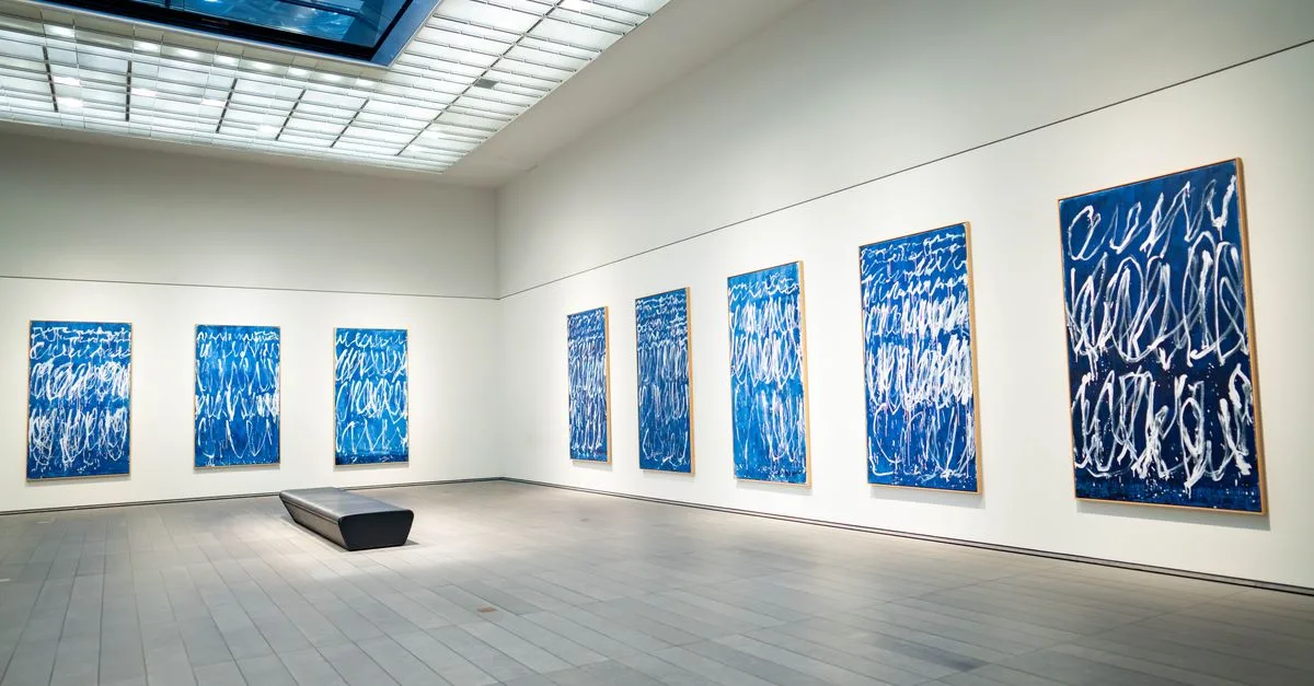Spacious modern art gallery featuring a collection of blue abstract paintings on display.