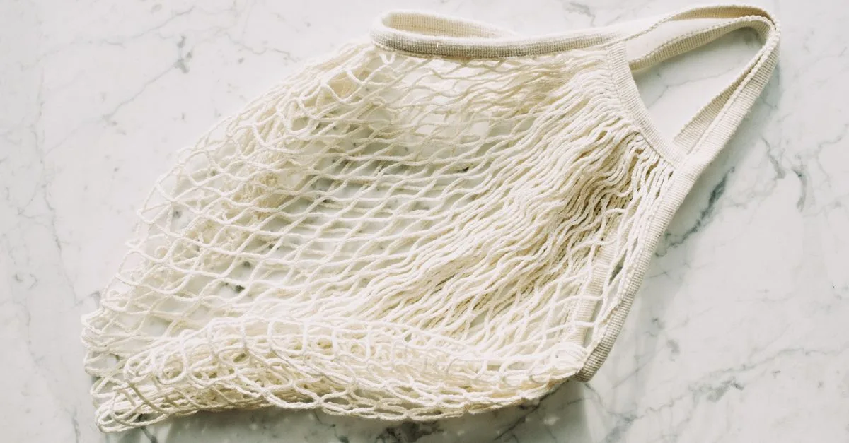 Top view of simple eco friendly white mesh bag arranged on marble surface in room