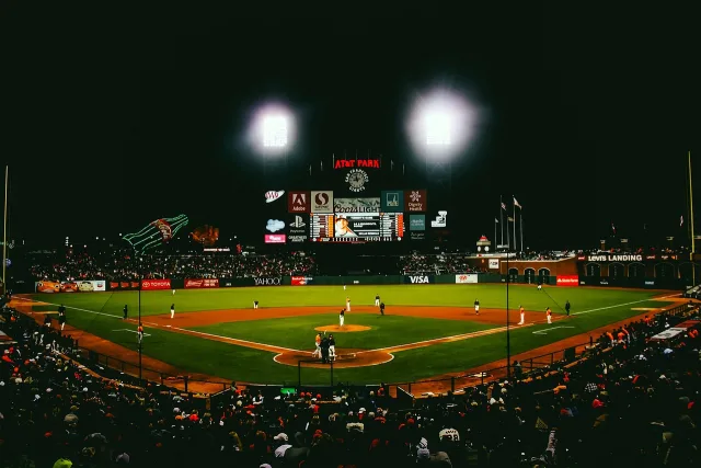 A professional baseball stadium under bright stadium lights during a night game.